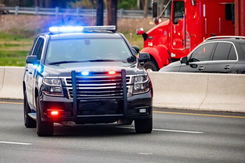a police car driving down the road next to a red truck