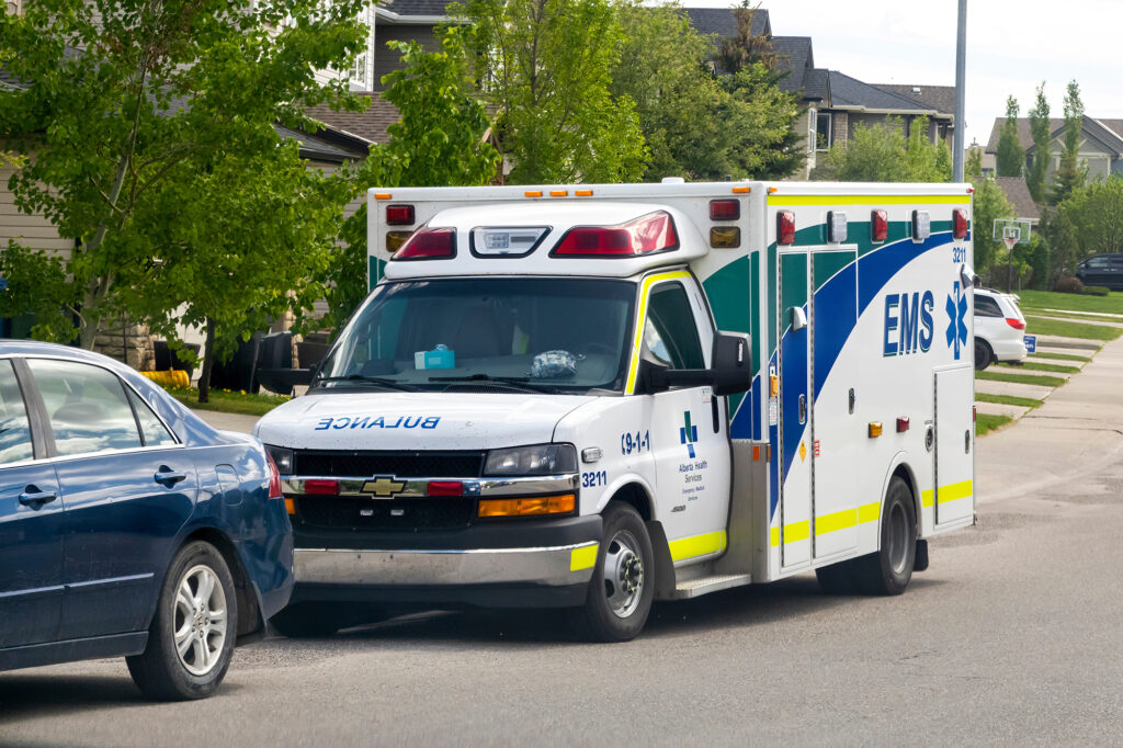 an ambulance is parked next to a blue car